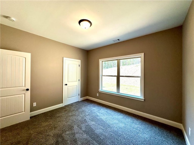 unfurnished bedroom featuring dark colored carpet, visible vents, and baseboards