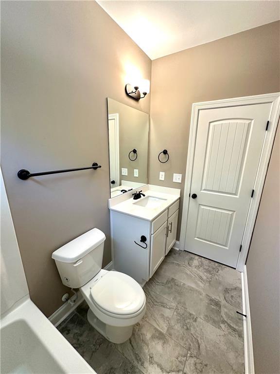 bathroom featuring toilet, marble finish floor, vanity, and baseboards