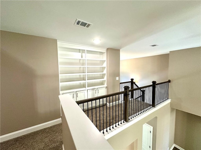 corridor featuring baseboards, visible vents, dark carpet, and an upstairs landing