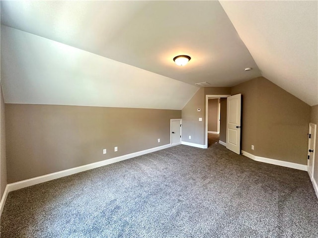 additional living space with lofted ceiling, dark carpet, and baseboards