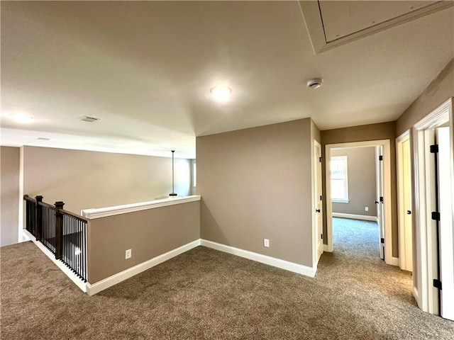 carpeted spare room with attic access, visible vents, and baseboards