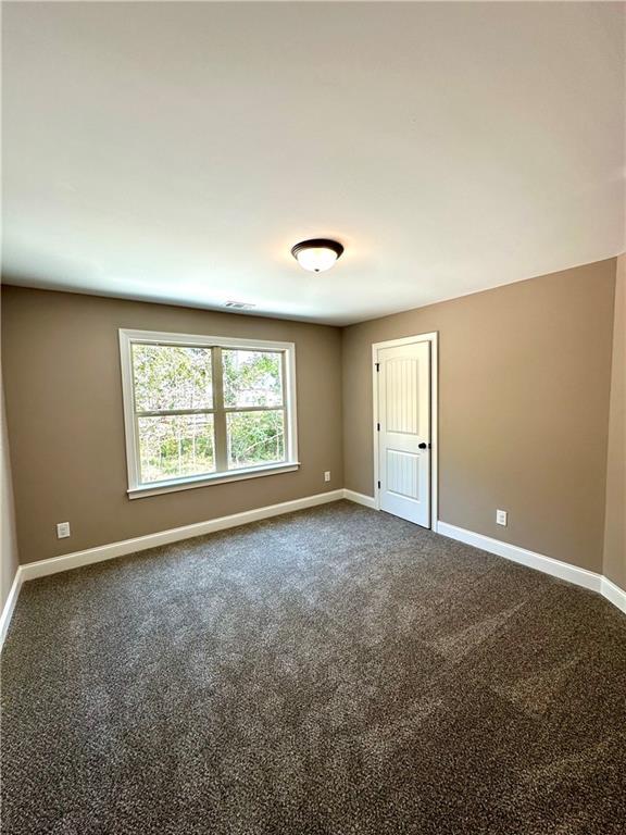 carpeted empty room with visible vents and baseboards