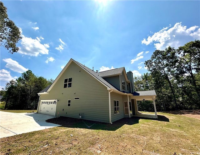 view of side of home featuring concrete driveway, a yard, a chimney, and an attached garage