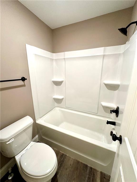 bathroom featuring tub / shower combination, wood finished floors, and toilet