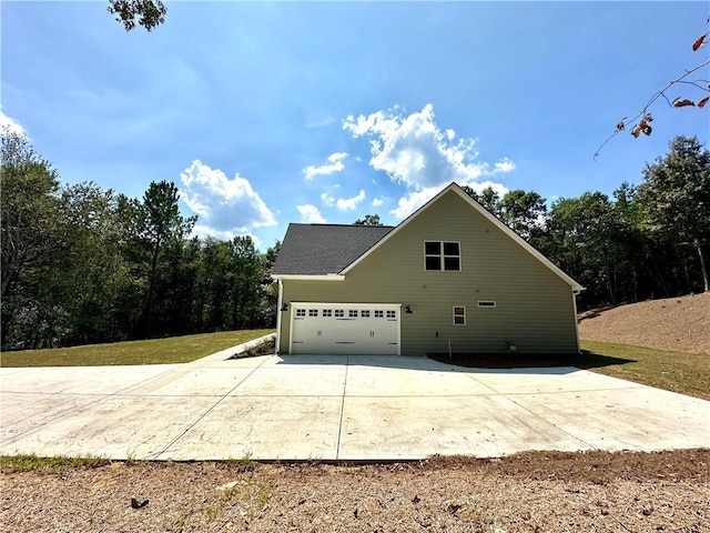 view of side of property featuring a garage and concrete driveway