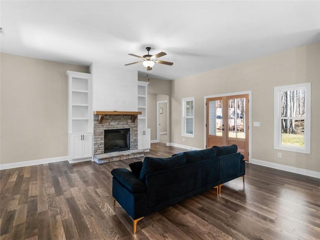 living room with french doors, dark wood finished floors, a stone fireplace, and baseboards