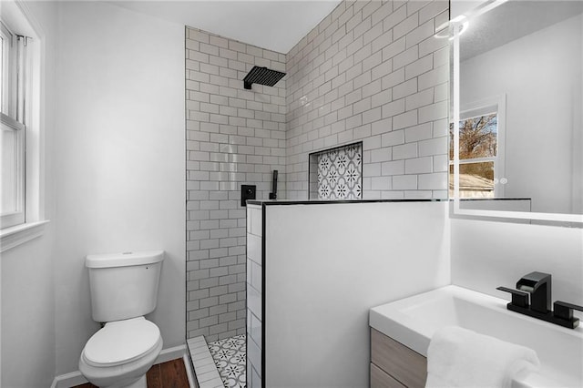 bathroom with vanity, toilet, and a tile shower