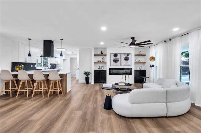 living room with ceiling fan, light hardwood / wood-style floors, and sink