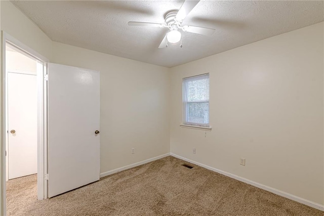 empty room featuring light carpet, ceiling fan, and a textured ceiling