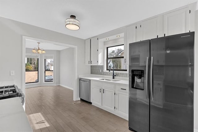 kitchen featuring sink, white cabinets, stainless steel dishwasher, light hardwood / wood-style floors, and fridge with ice dispenser