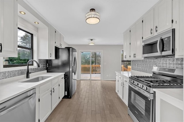 kitchen featuring sink, white cabinetry, tasteful backsplash, appliances with stainless steel finishes, and light hardwood / wood-style floors