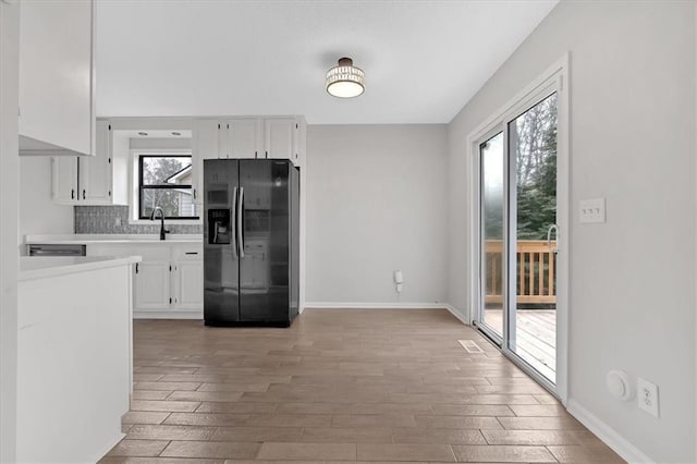 kitchen featuring white cabinetry, backsplash, black refrigerator with ice dispenser, and hardwood / wood-style flooring