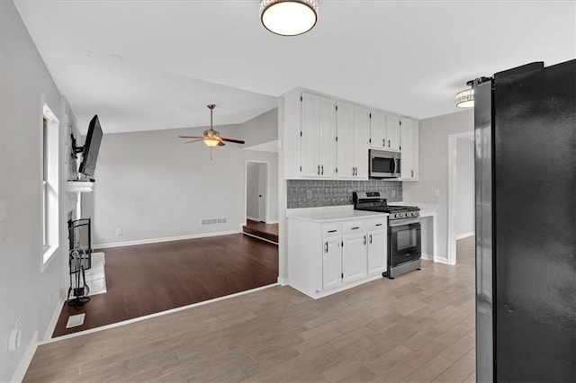 kitchen featuring lofted ceiling, white cabinets, decorative backsplash, ceiling fan, and stainless steel appliances