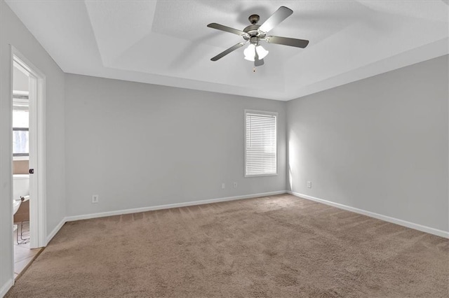 carpeted empty room featuring a raised ceiling and ceiling fan