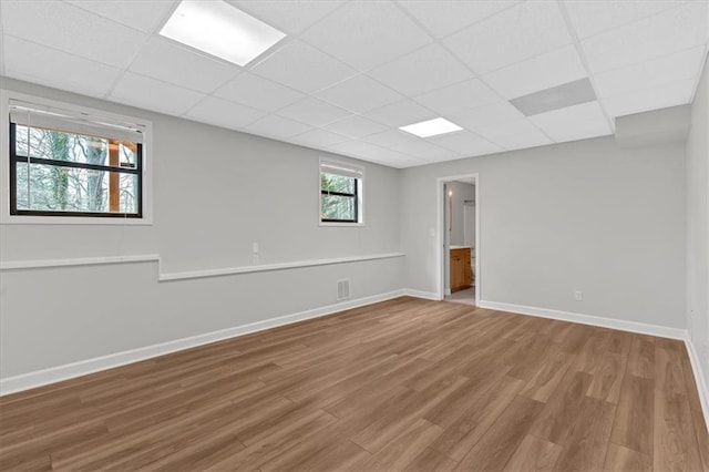 basement with a paneled ceiling and wood-type flooring