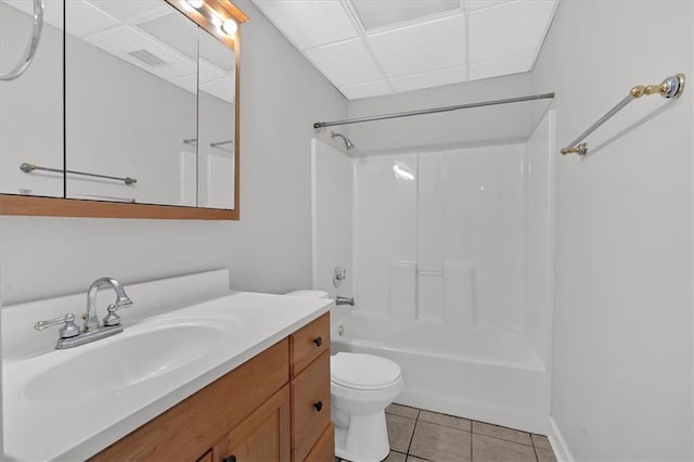 full bathroom featuring tile patterned flooring, vanity, a drop ceiling, shower / bathtub combination, and toilet