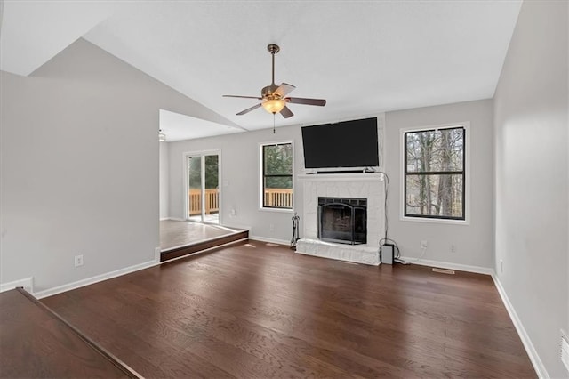 unfurnished living room featuring a stone fireplace, dark wood-type flooring, ceiling fan, and vaulted ceiling