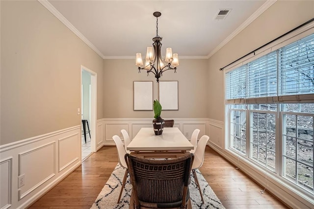 dining space featuring crown molding, light hardwood / wood-style floors, and an inviting chandelier