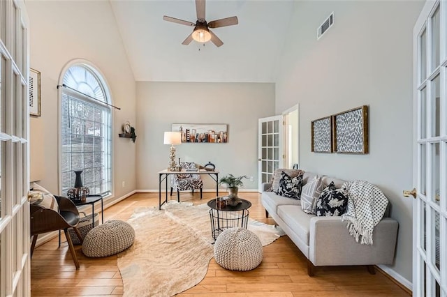 living room featuring ceiling fan, light hardwood / wood-style floors, high vaulted ceiling, and french doors