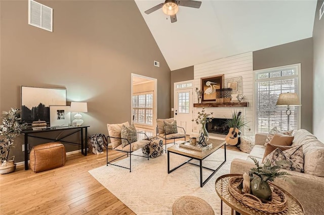 living room featuring a fireplace, ceiling fan, light hardwood / wood-style flooring, and high vaulted ceiling