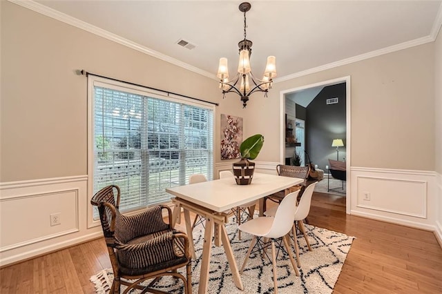 dining room featuring light wood-type flooring, crown molding, and a chandelier