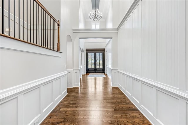 interior space with wood finished floors, a decorative wall, a notable chandelier, and french doors