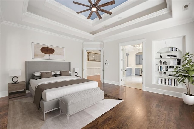 bedroom with a raised ceiling, crown molding, wood finished floors, and visible vents