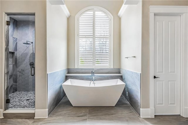 bathroom featuring a shower stall, a soaking tub, tile walls, and a wainscoted wall