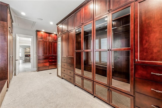 walk in closet with attic access and light colored carpet