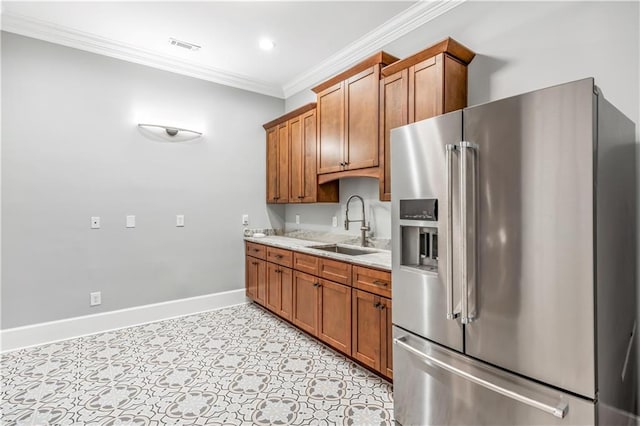 kitchen featuring brown cabinets, ornamental molding, a sink, stainless steel fridge with ice dispenser, and baseboards