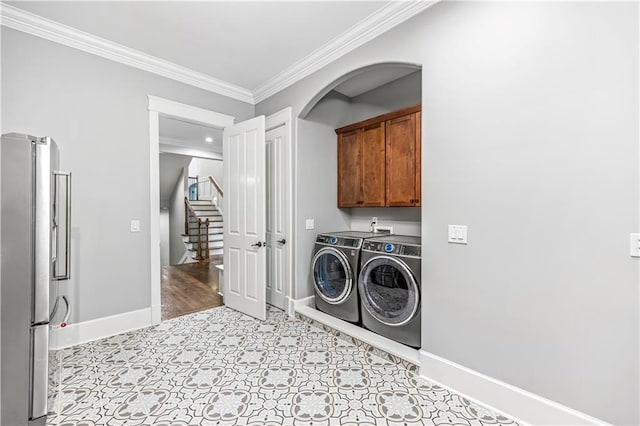 clothes washing area featuring baseboards, cabinet space, independent washer and dryer, and crown molding