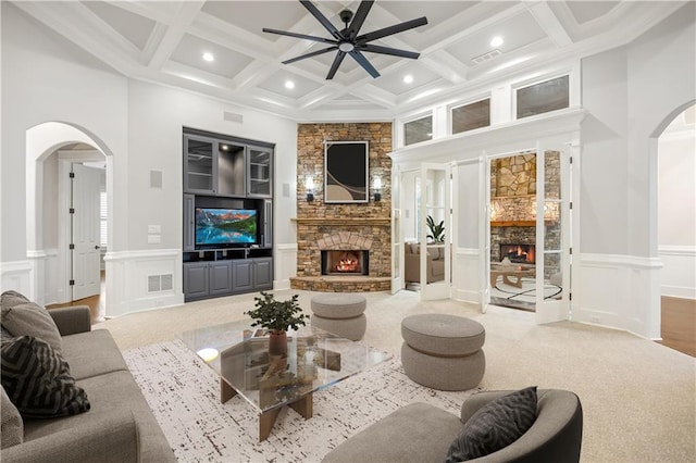 living area featuring arched walkways, a stone fireplace, and beamed ceiling