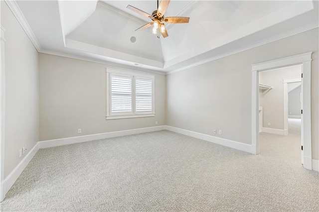 carpeted spare room with crown molding, baseboards, a tray ceiling, vaulted ceiling, and a ceiling fan