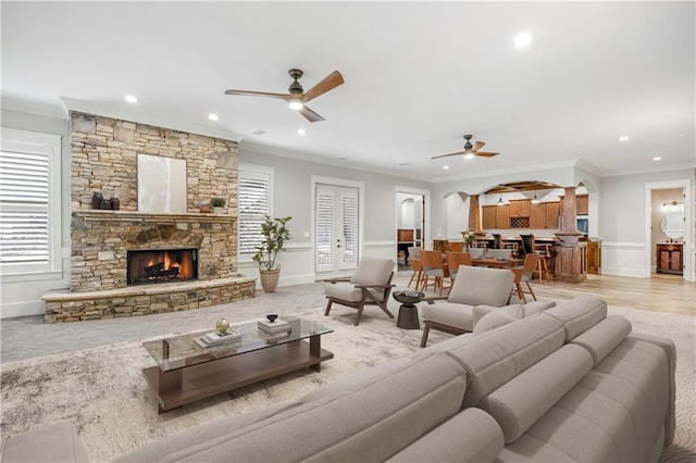 living area with a fireplace, crown molding, and ceiling fan