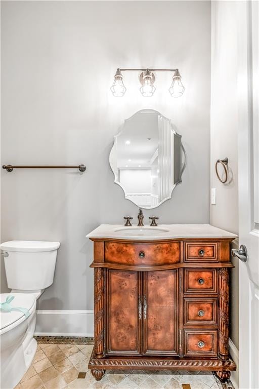 half bath featuring vanity, toilet, and baseboards