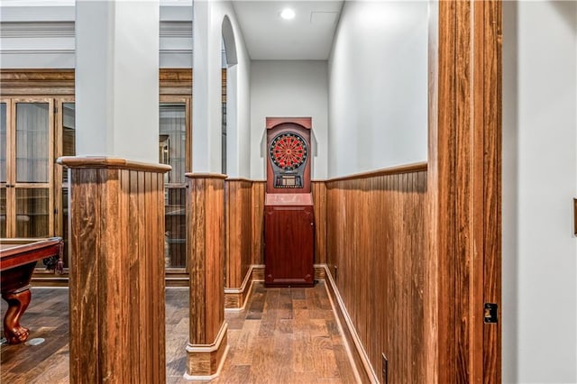 hall featuring wooden walls, wainscoting, and wood finished floors