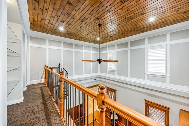 corridor with recessed lighting, wooden ceiling, a decorative wall, an upstairs landing, and dark colored carpet