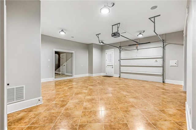 garage featuring visible vents, a garage door opener, and baseboards