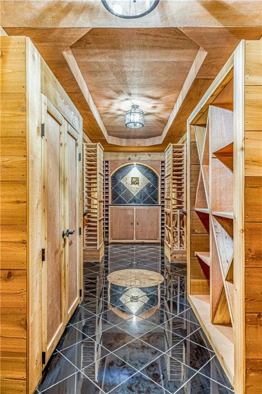 wine area featuring tile patterned floors, a tray ceiling, and wooden ceiling