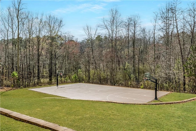 view of basketball court with community basketball court, a view of trees, and a yard