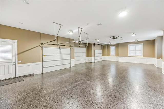 garage with a decorative wall, wainscoting, a garage door opener, and ceiling fan