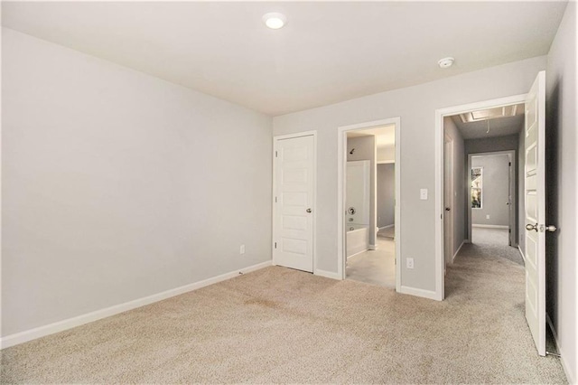 unfurnished bedroom featuring ensuite bathroom and light colored carpet