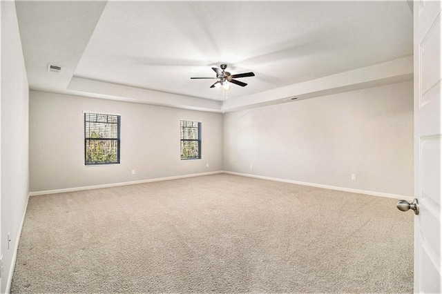 carpeted spare room featuring a raised ceiling and ceiling fan