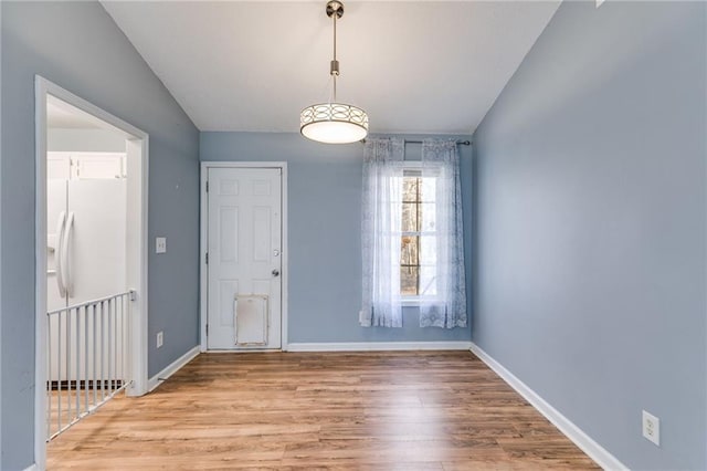 unfurnished dining area with light wood-style flooring and baseboards