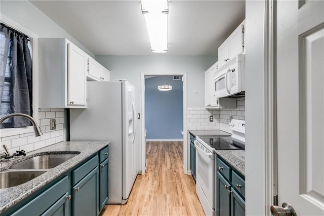 kitchen with white appliances, a sink, white cabinets, light wood-type flooring, and decorative light fixtures