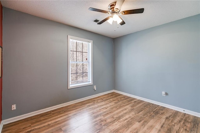 unfurnished room featuring a textured ceiling, light wood-type flooring, a ceiling fan, and baseboards