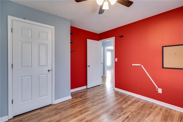 interior space featuring a ceiling fan, baseboards, and wood finished floors