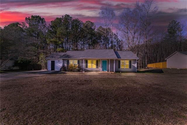 ranch-style house featuring a shingled roof and a front yard