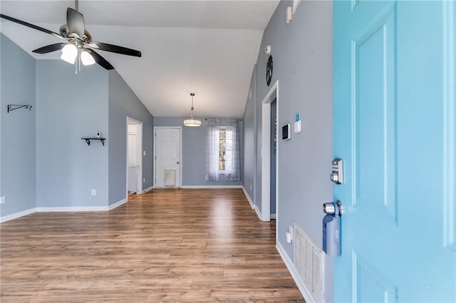 foyer with lofted ceiling, baseboards, visible vents, and wood finished floors