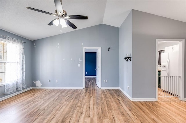 unfurnished room featuring light wood-type flooring, vaulted ceiling, baseboards, and ceiling fan